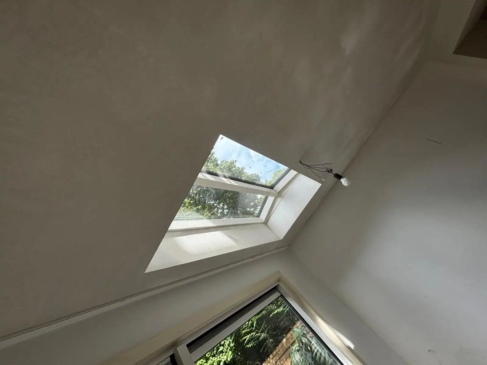Schuin gestuct plafond met dakraam, van onderen gezien.